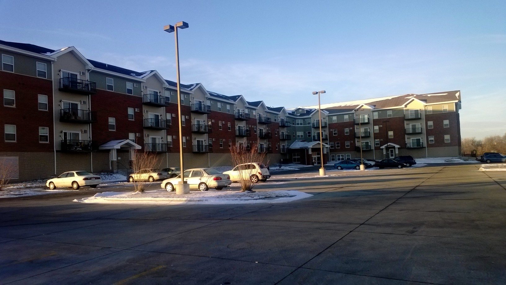 A parking lot with cars and apartment buildings in the background.
